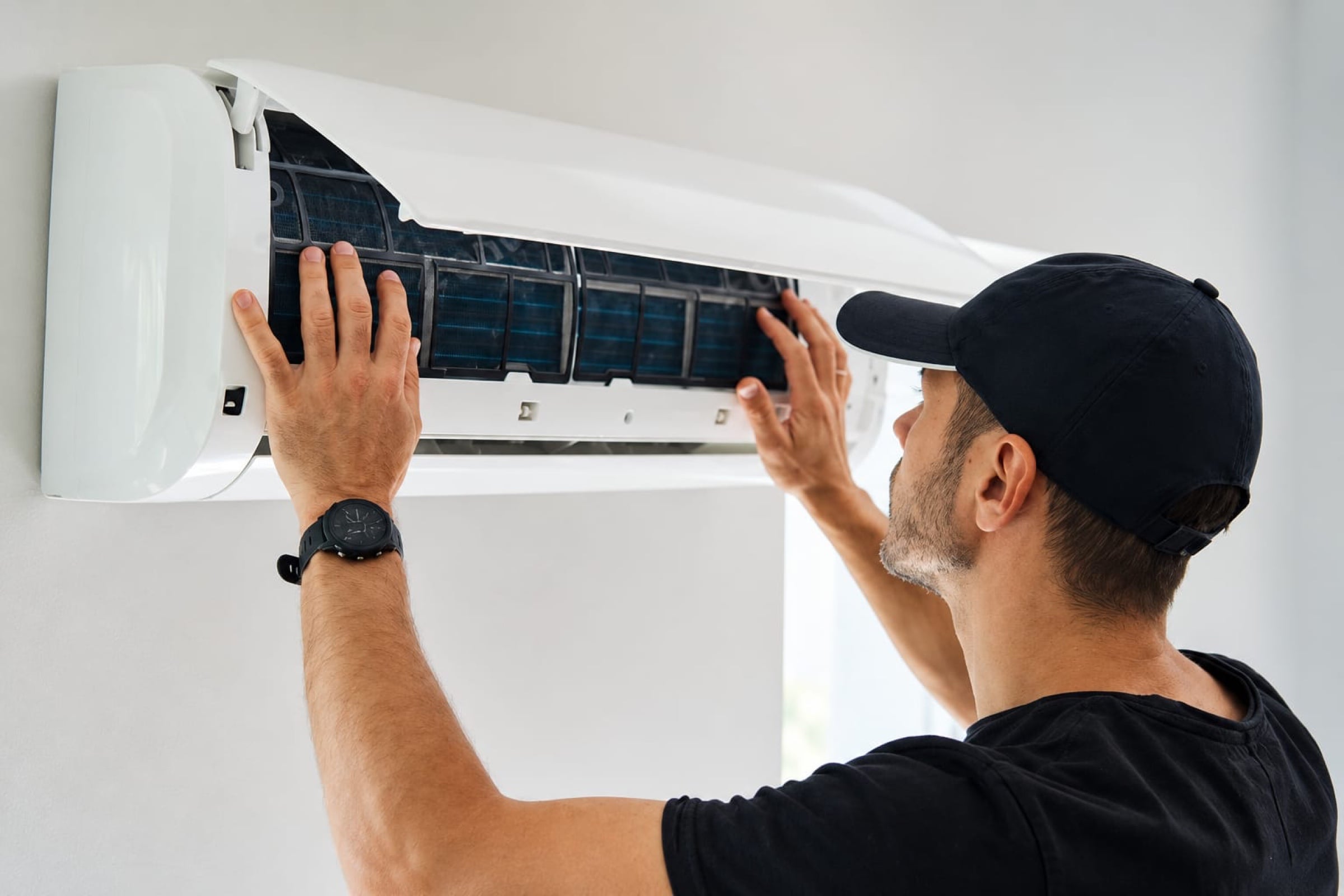 Technician taking the filters out of a high-wall heat pump to clean them